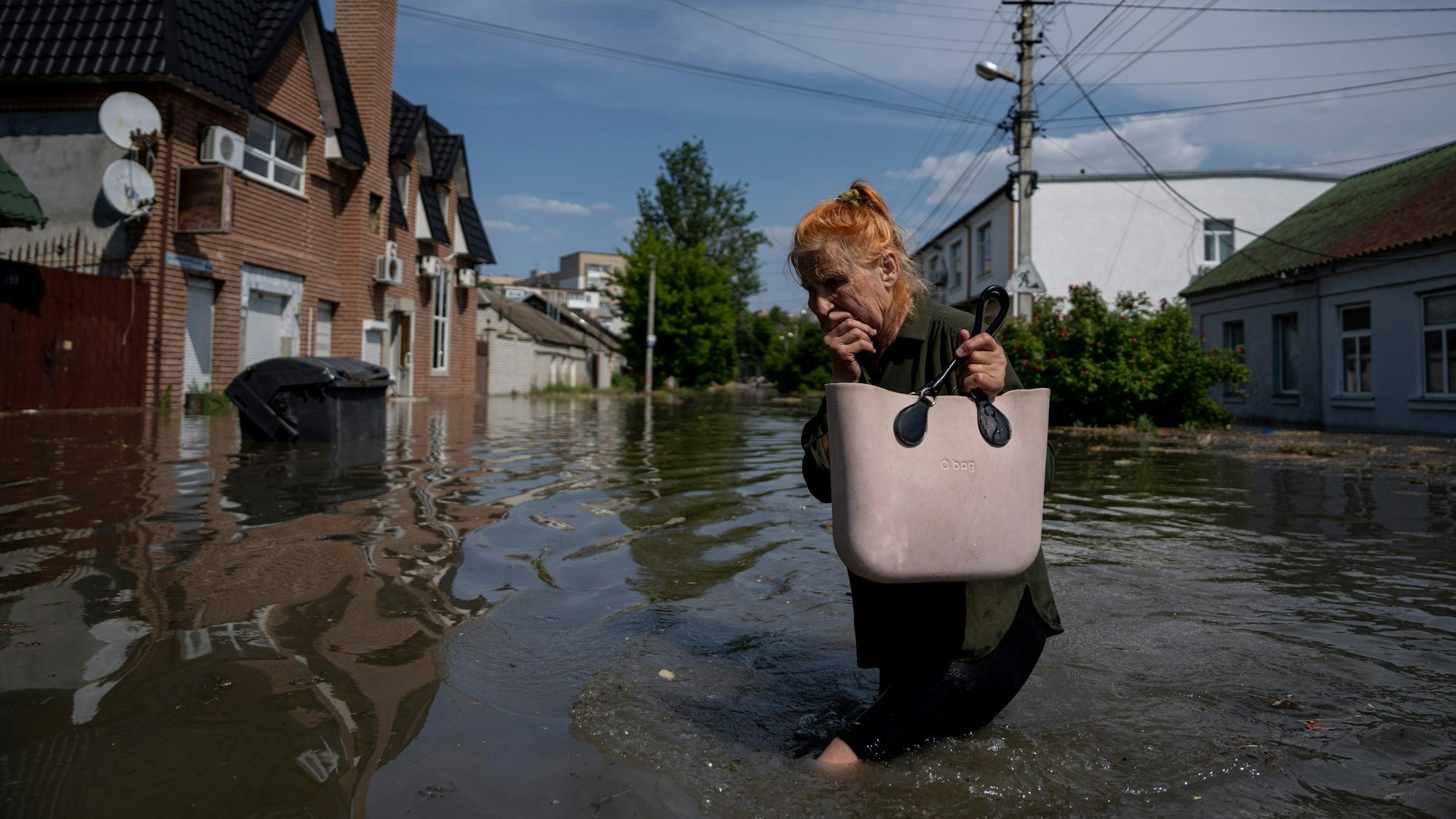 6. Juni 2023, Ukraine, Cherson: Eine Anwohnerin bahnt sich einen Weg durch eine überflutete Straße.