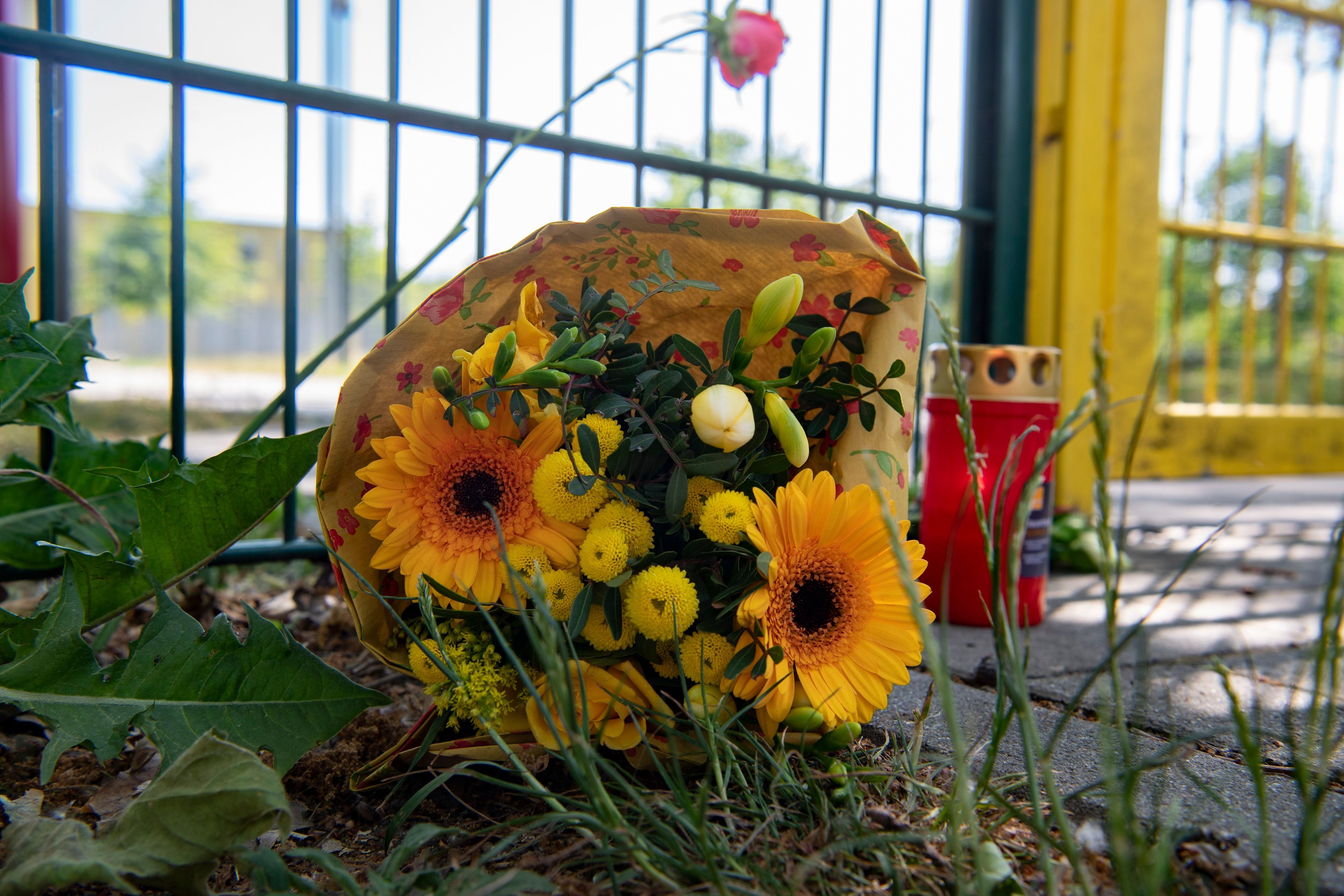 Blumen und eine Kerze erinnern liegen an einem Zaun in Lichtenberg.