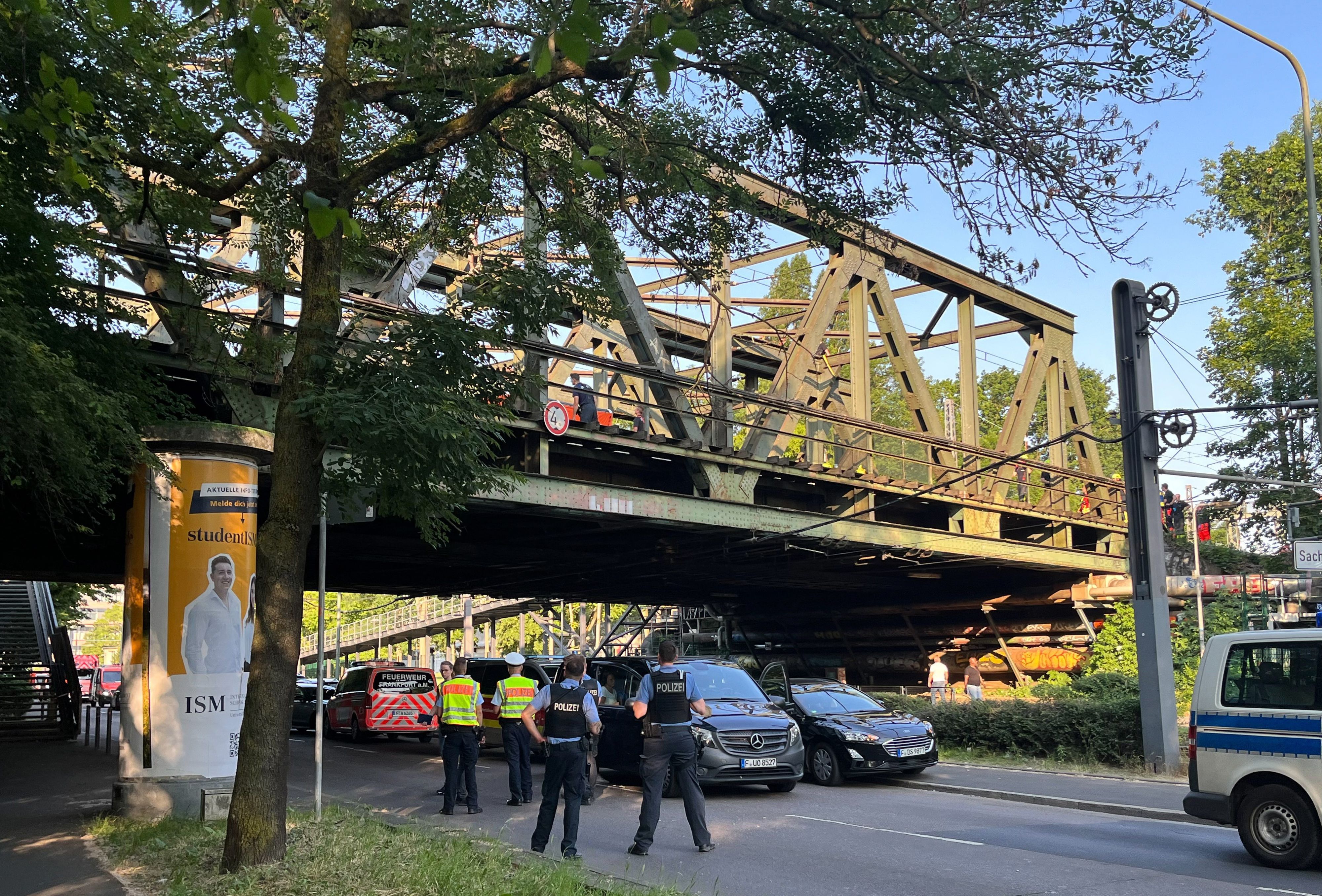 Einsatzkräfte stehen auf und unter einer Eisenbahnbrücke. Der Polizeieinsatz unweit des Frankfurter Hauptbahnhofs führte Montagnachmittag zu zahlreichen Zugausfällen sowohl im Nah- als auch im Fernverkehr.