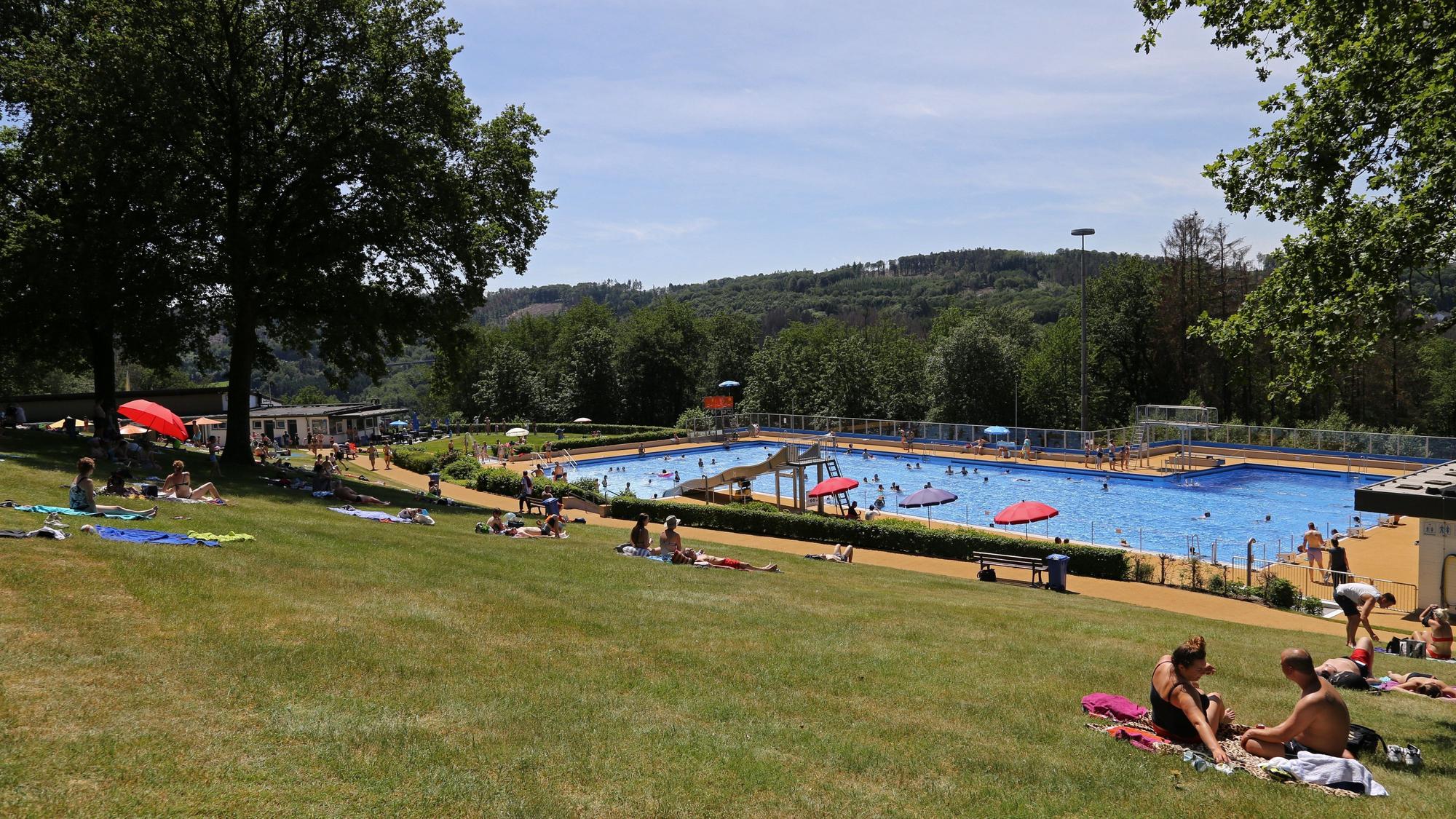 Das Panoramabad in Engelskirchen in einer Übersicht. Auf der Wiese sitzen einige Badegäste, andere schwimmen im Wasser im Hintergrund.