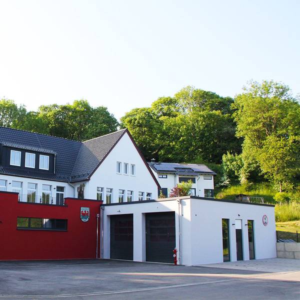 Das Bild zeigt vorne den Neubau des Feuerwehrgerätehauses in Kronenburg, dahinter und etwas erhöht im Hang das Dorfgemeinschaftshaus.
