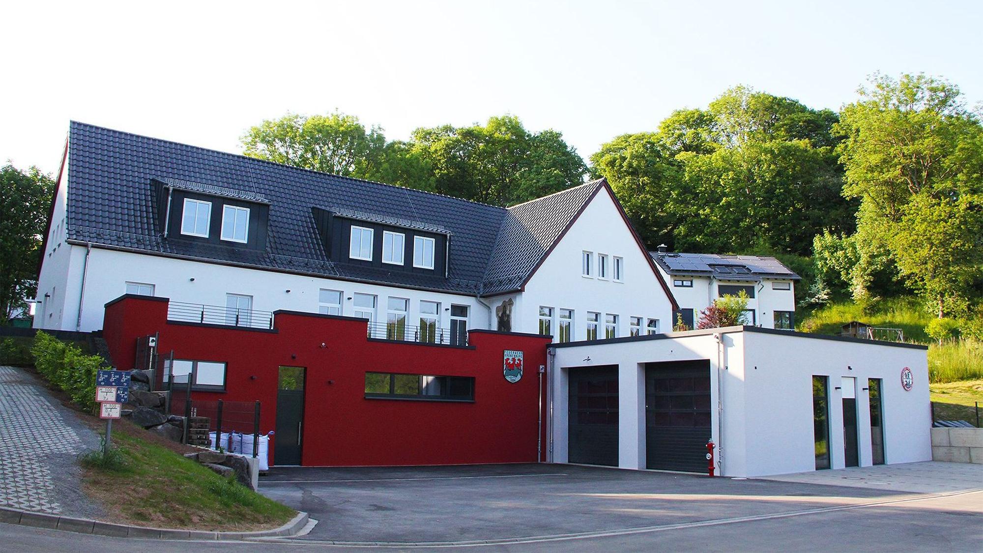 Das Bild zeigt vorne den Neubau des Feuerwehrgerätehauses in Kronenburg, dahinter und etwas erhöht im Hang das Dorfgemeinschaftshaus.