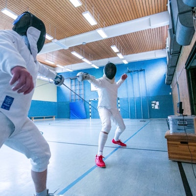 Zwei Sportler im Ganzkörper-Schutzanzug fechten.