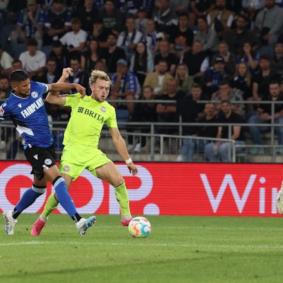 06.06.2023, Nordrhein-Westfalen, Bielefeld: Fußball: 2. Bundesliga - Relegation, Arminia Bielefeld - SV Wehen Wiesbaden, Relegation, Rückspiele, Schüco Arena. Bielefelds Andrés Andrade (l) und Benedict Hollerbach (M) im Zweikampf vor dem Bielefelder Torhüter Martin Fraisl (r).
