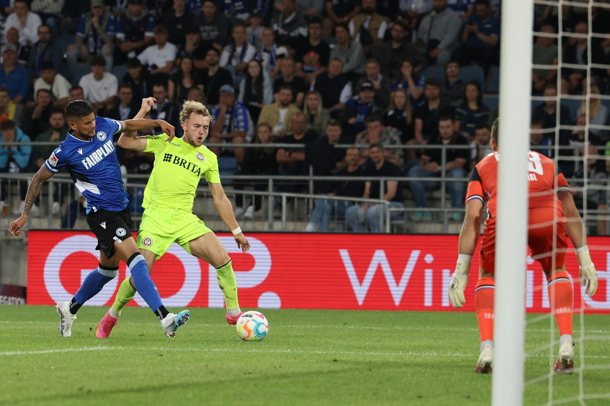 06.06.2023, Nordrhein-Westfalen, Bielefeld: Fußball: 2. Bundesliga - Relegation, Arminia Bielefeld - SV Wehen Wiesbaden, Relegation, Rückspiele, Schüco Arena. Bielefelds Andrés Andrade (l) und Benedict Hollerbach (M) im Zweikampf vor dem Bielefelder Torhüter Martin Fraisl (r).