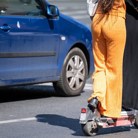 Zwei Frauen stehen auf einem E-Scooter.