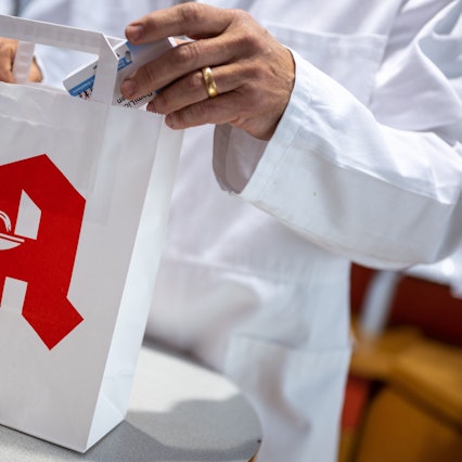 ILLUSTRATION - 05.06.2023, Berlin: Ein Apotheker legt in einer Apotheke eine Packung mit Tabletten in eine Papiertasche mit Apotheken-Logo. Foto: Monika Skolimowska/dpa +++ dpa-Bildfunk +++