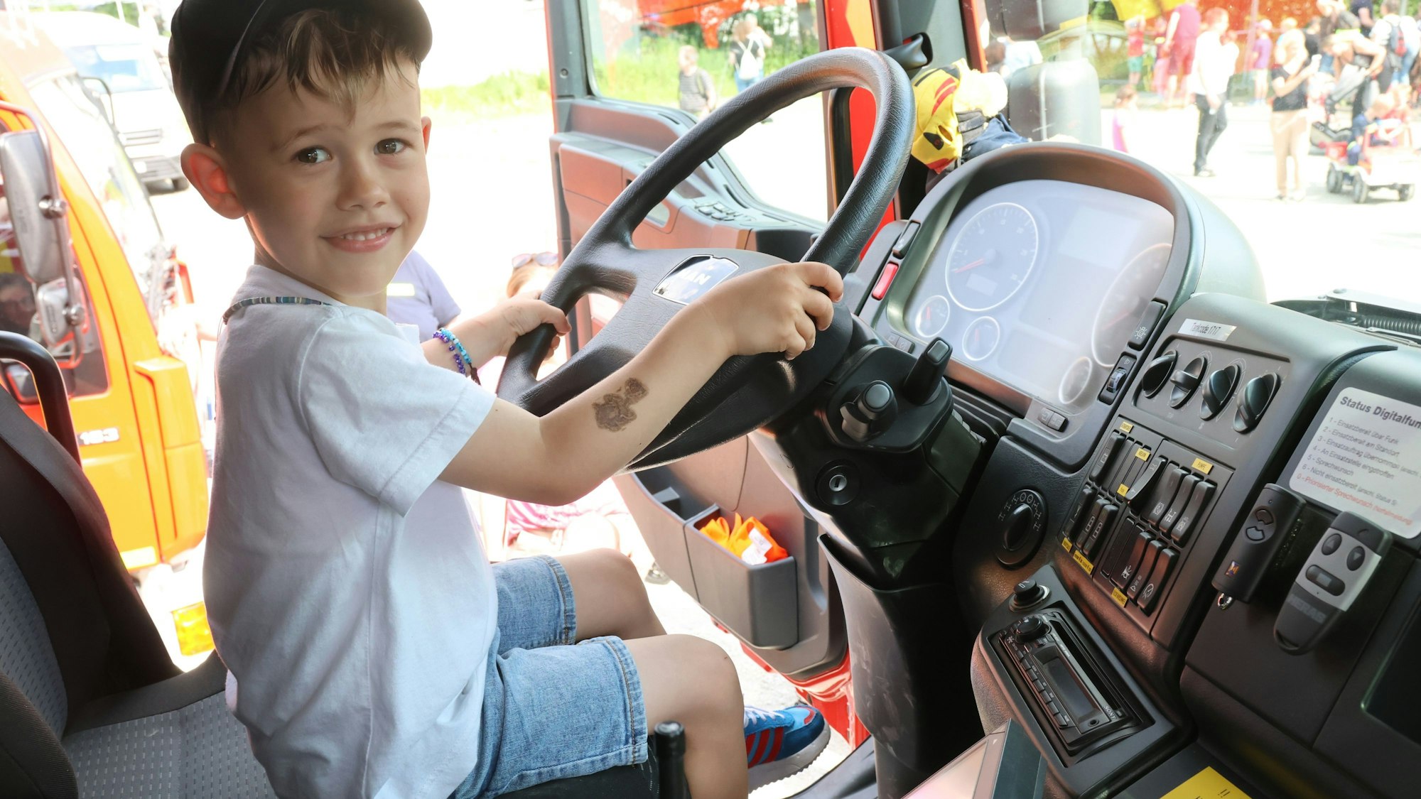 Ein Kind aus Eckenhagen sitzt am Steuer eines Feuerwehrautos.