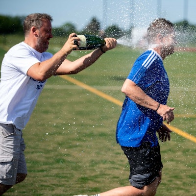 Wißkirchens Trainer Kevin Greuel versucht vor der Sektdusche nach dem geglückten Aufstieg zu entkommen. Vergebens.