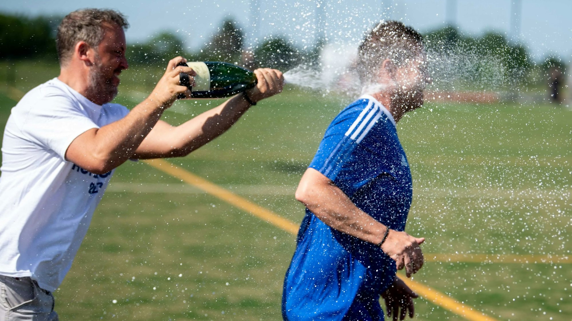 Wißkirchens Trainer Kevin Greuel versucht vor der Sektdusche nach dem geglückten Aufstieg zu entkommen. Vergebens.