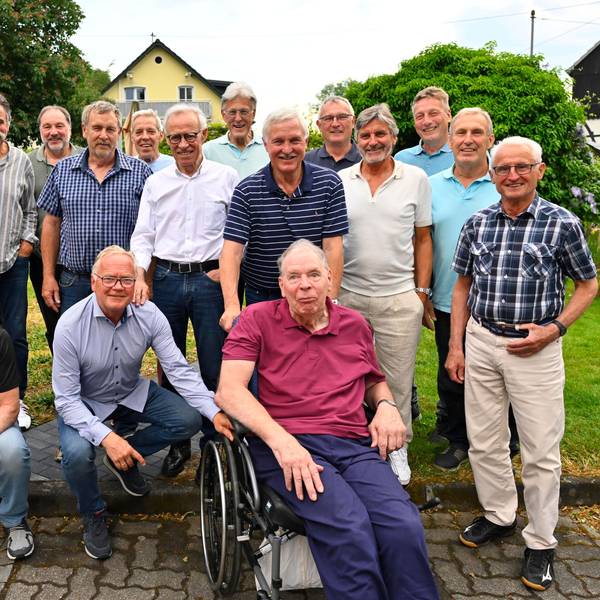 Eine Gruppe von Männern steht beisammen. Einer von ihnen sitzt im Rollstuhl.