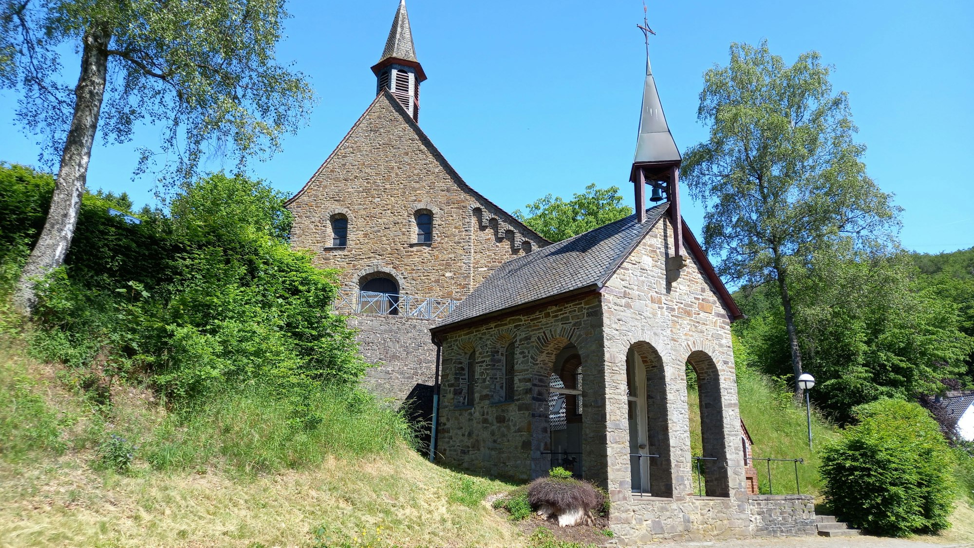 Eine steinerne Kirche steht in einer grünen Landschaft.