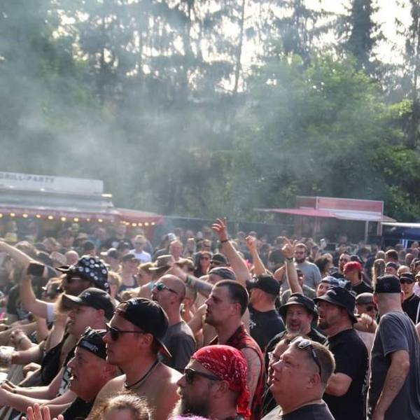 Menschen stehen in einer Menge vor einer Bühne.
