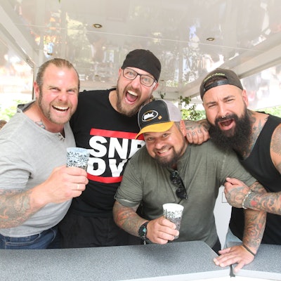 Vier Männer stehen in einem Bierpilz.