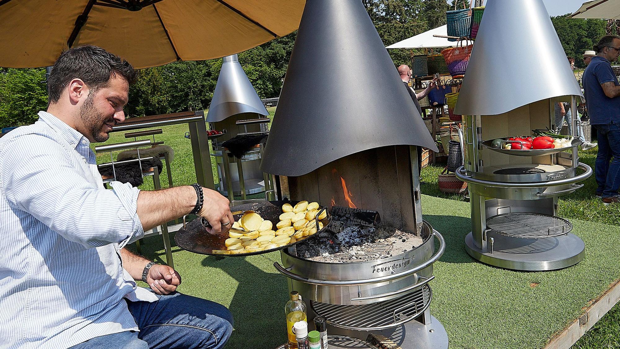 Das Bild zeigt einen Mann, der einen Grillkamin mit Kartoffelscheiben bestückt, um diese zu garen.