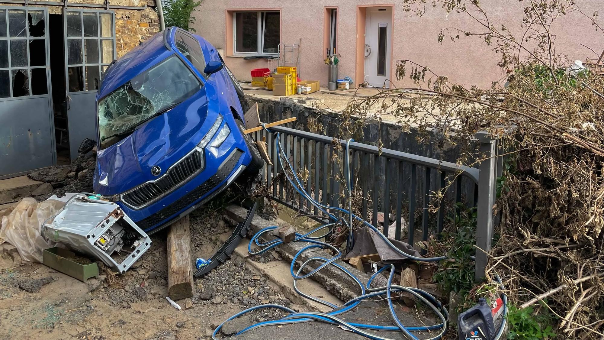 Das Bild zeigt die Zerstörung nach der Flut in Kreuzweingarten. Ein Auto ist auf ein Geländer gespült worden.