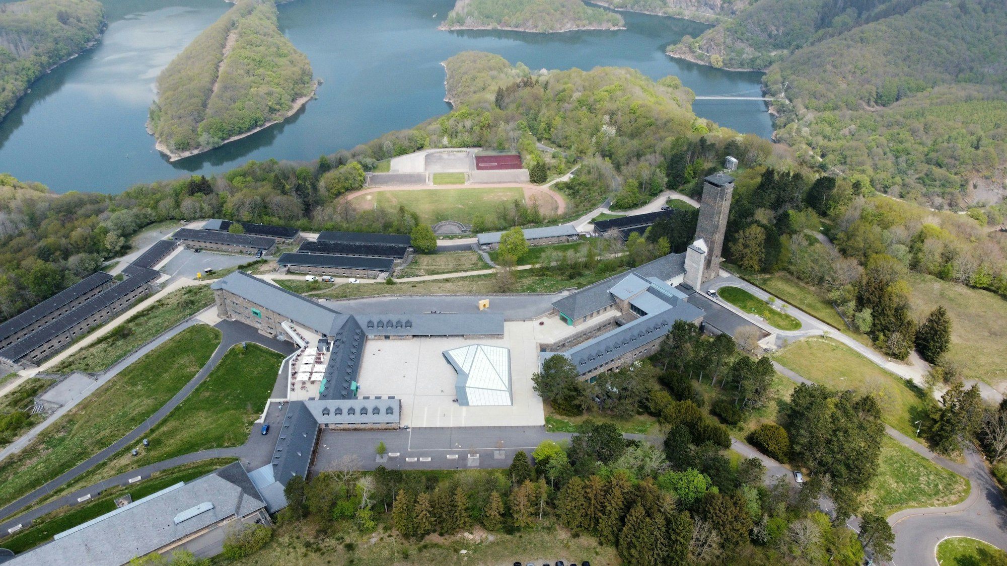 Das Luftbild zeigt den Bereich rund um den Adlerhof in Vogelsang, im Hintergrund den Urftsee.