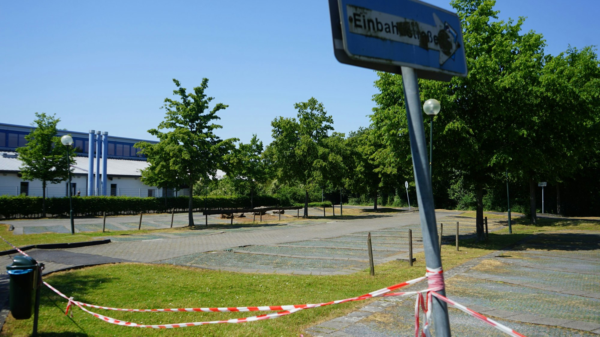 Der Parkplatz an der Erftlagune. Im Vordergrund ein schief stehendes Einbahnstraßen-Schild und rot-weißes Flatterband.