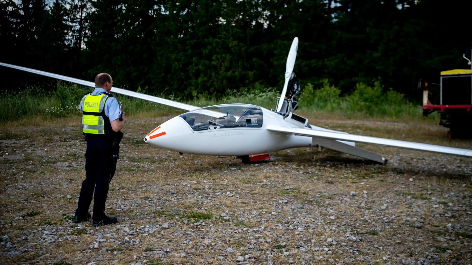 Ein Polizist steht vor dem abgestürzten Segelflugzeug.