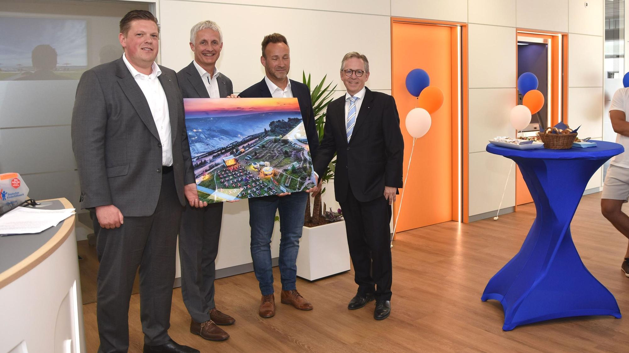 Bürgermeister Andreas Heller (2.v.r.) überreichte ein Bild zur Wiedereröffnung der Volksbank-Hauptstelle an Regionalleiter Martin Drösser sowie die Vorstände Patrick Grosche und Volker Leisten (v.r.).