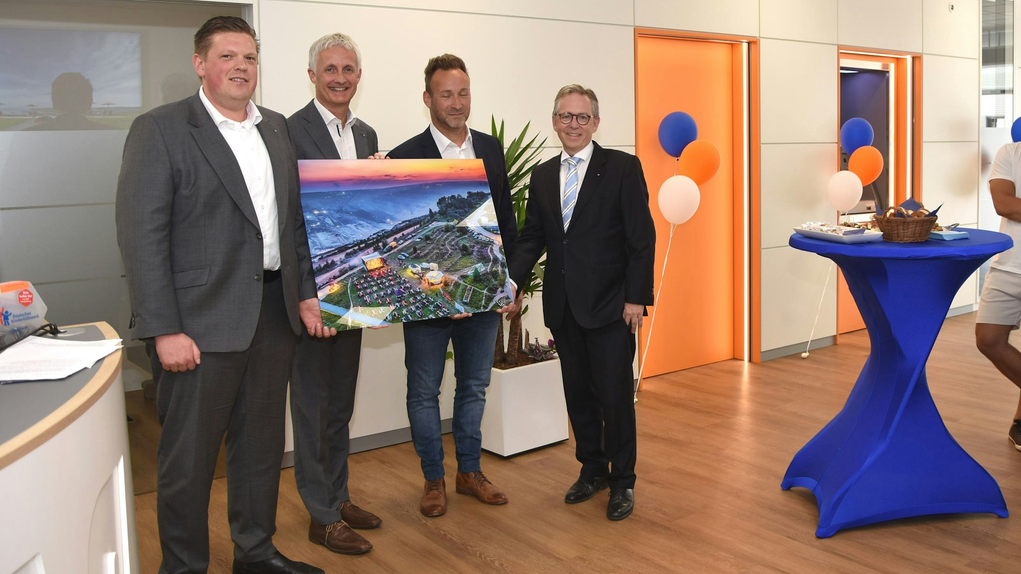 Bürgermeister Andreas Heller (2.v.r.) überreichte ein Bild zur Wiedereröffnung der Volksbank-Hauptstelle an Regionalleiter Martin Drösser sowie die Vorstände Patrick Grosche und Volker Leisten (v.r.).