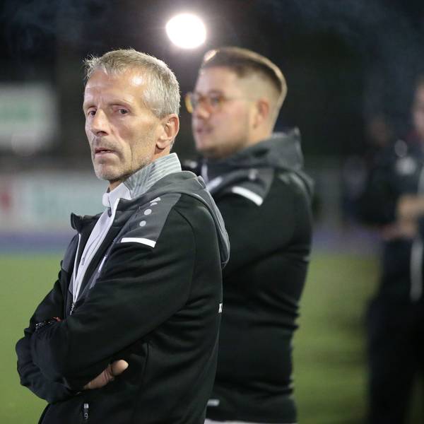 Ein Trainer steht am Rand eines Fußballfeldes.