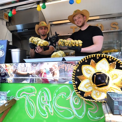 Zwei Männer mit Strohhüten stehen in einem Streetfood-Truck.