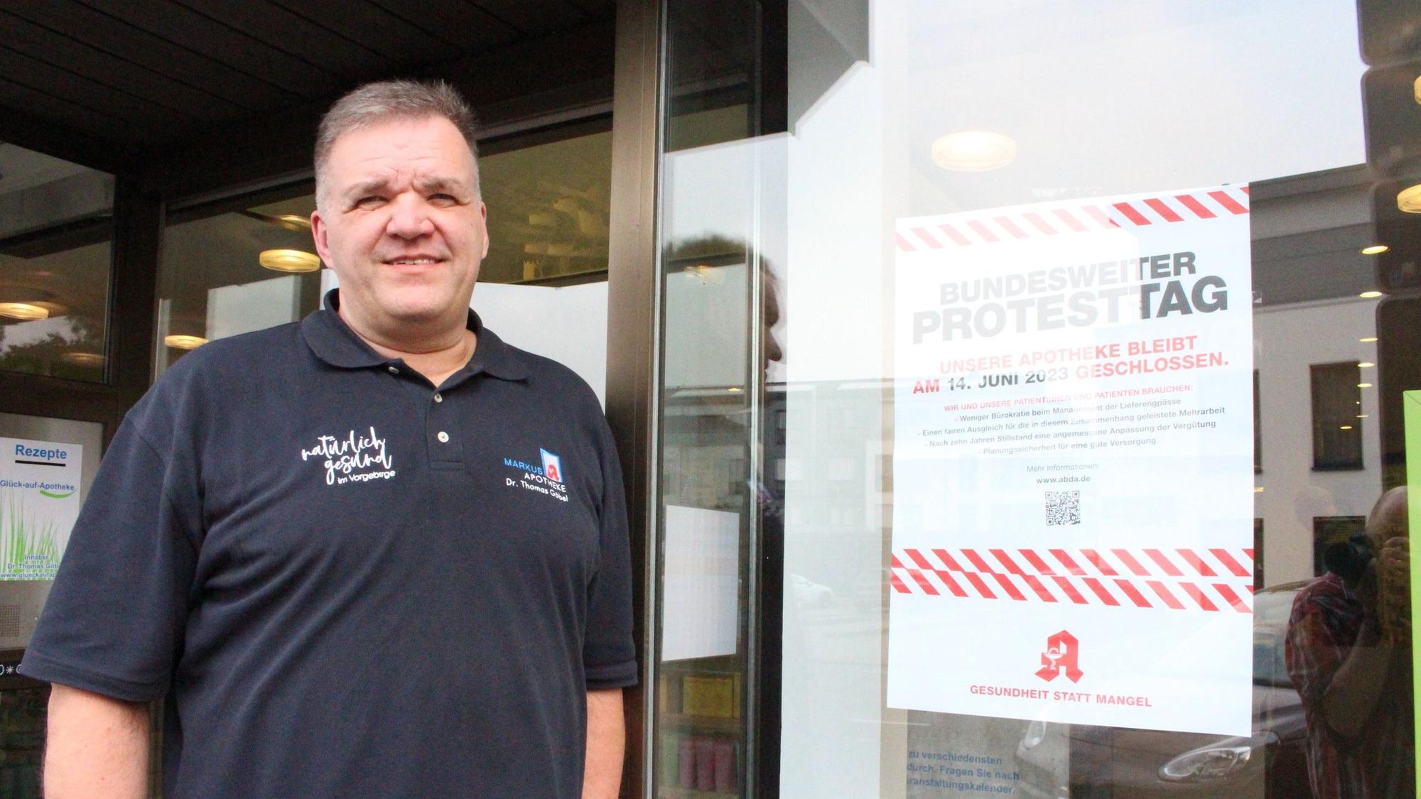 Das Bild zeigt Dr. Thomas Göbel vor seiner Apotheke in Mechernich. An der Tür hängt ein Plakat, das auf den Protesttag hinweist.