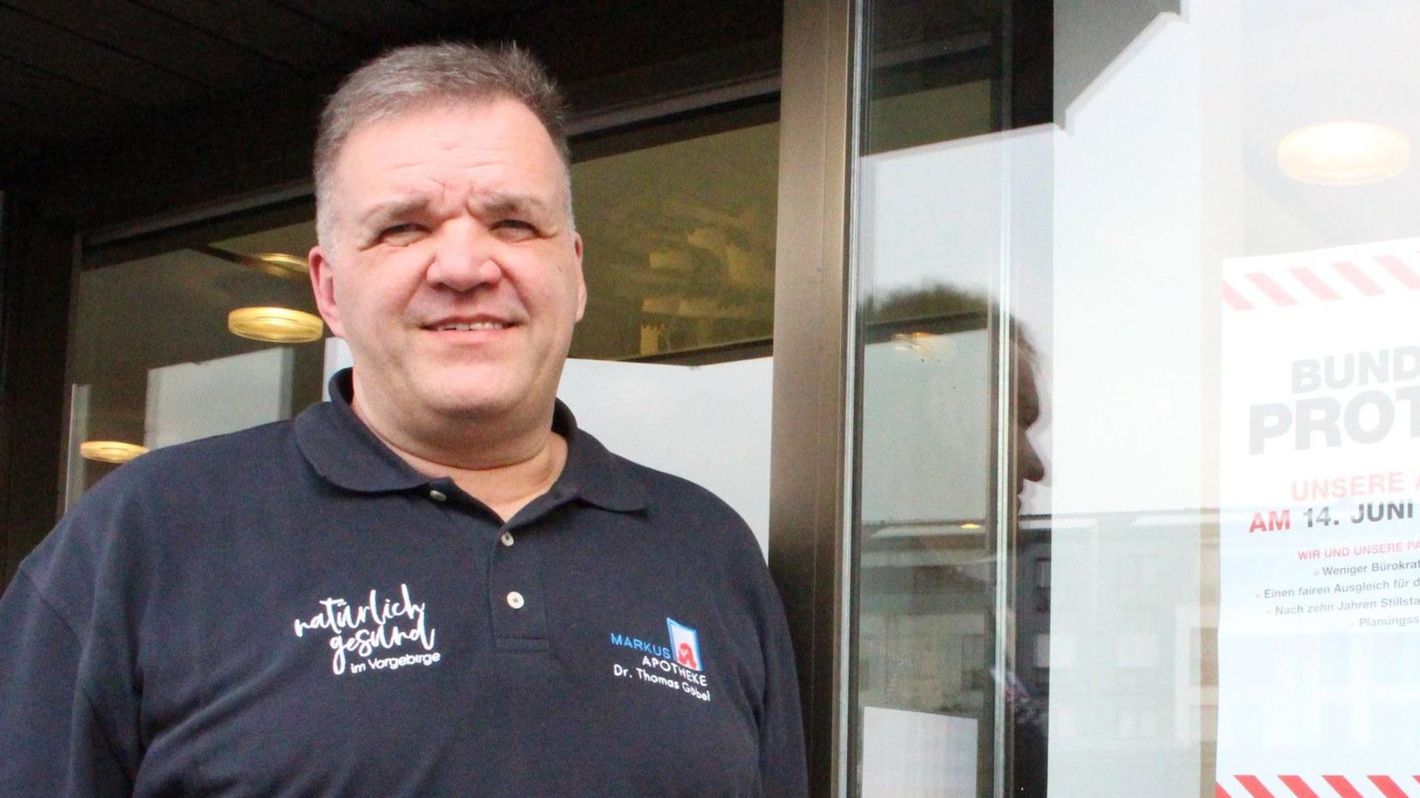 Dr. Thomas Göbel steht vor einer Apotheke.