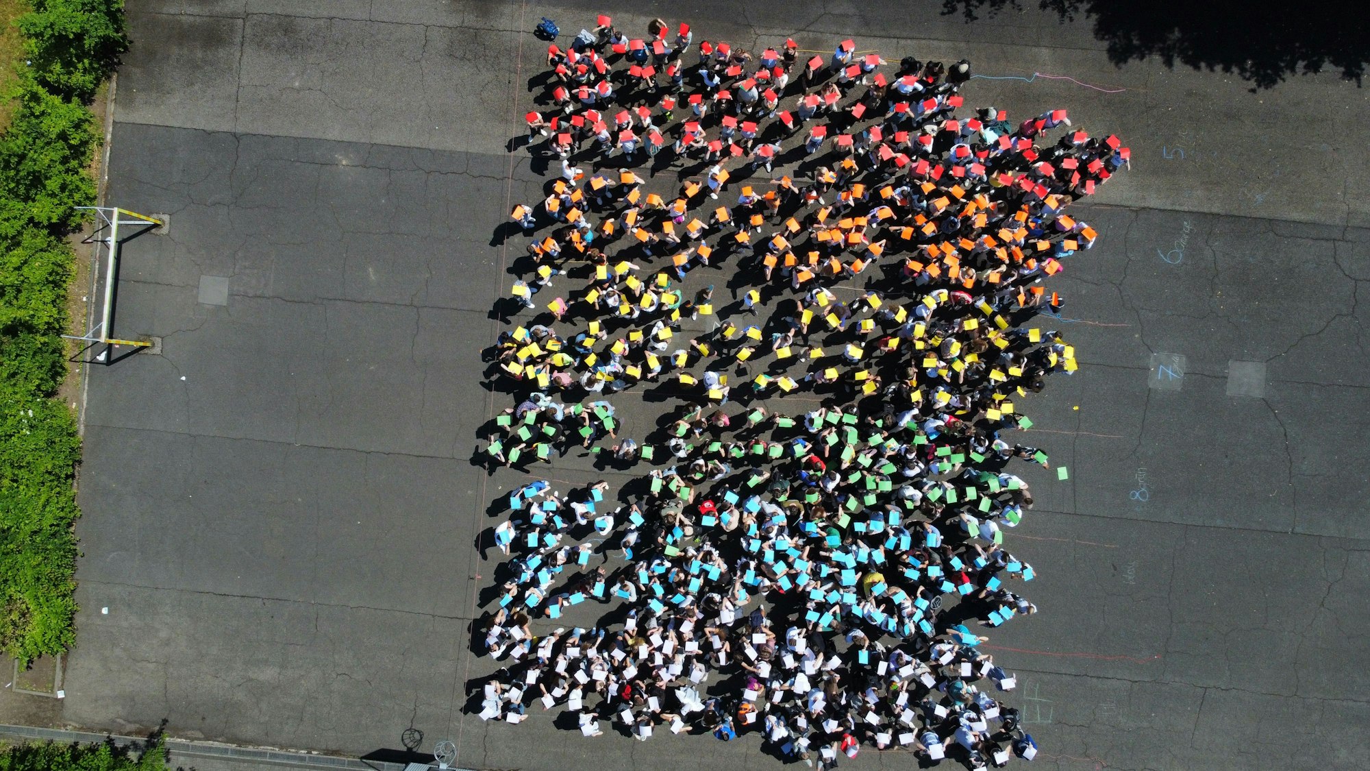 Schüler halten bunte Plakate hoch und stellen die Regenbogenflagge nach.