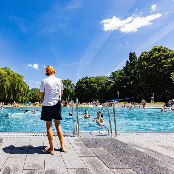 Ein Schwimmeister steht vor einem Freibad.