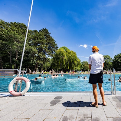 Ein Schwimmeister steht vor einem Freibad.