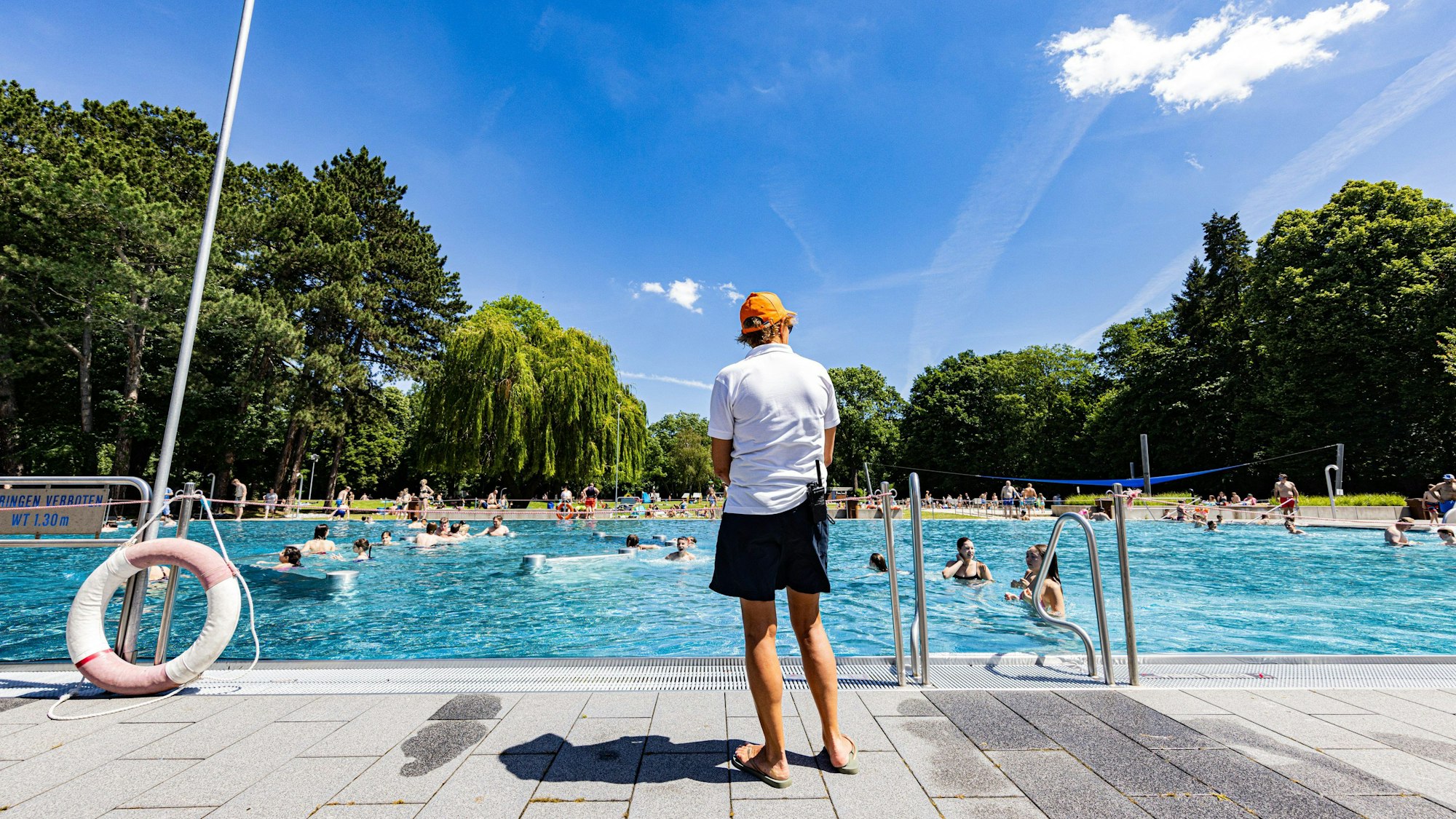 Ein Schwimmeister steht vor einem Freibad.