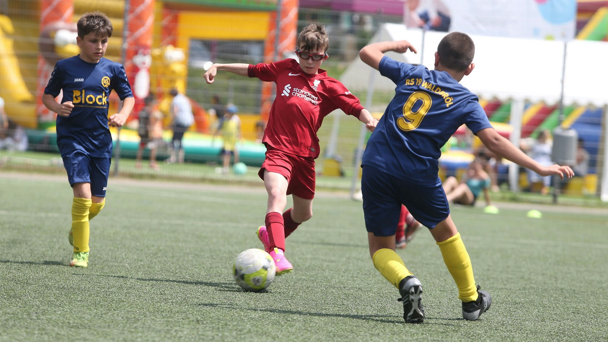 Mehrere Jungs in einer Fußball-Spielsituation. Ein Junge trägt eine Sportbrille.