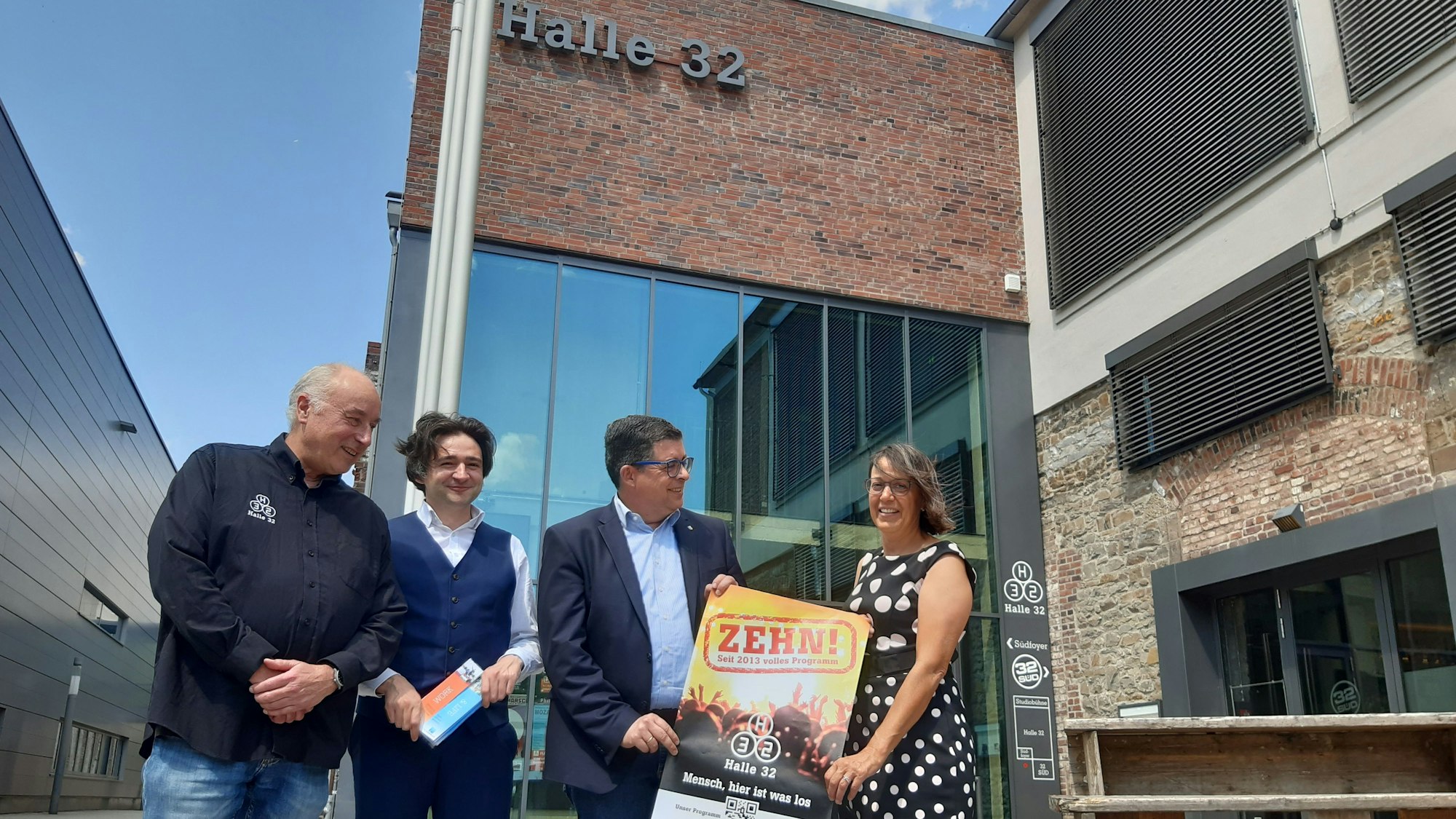 Martin Kuchejda und Ulrike Rösner von der Gummersbacher KultGM, Bürgermeister Frank Helmenstein und Hoteldirektor Alberto Perez an einem Jubiläumsplakat.