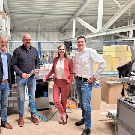 Drei Männer und eine Frau stehen in der Produktionshalle eines Unternehmens in Nettersheim.