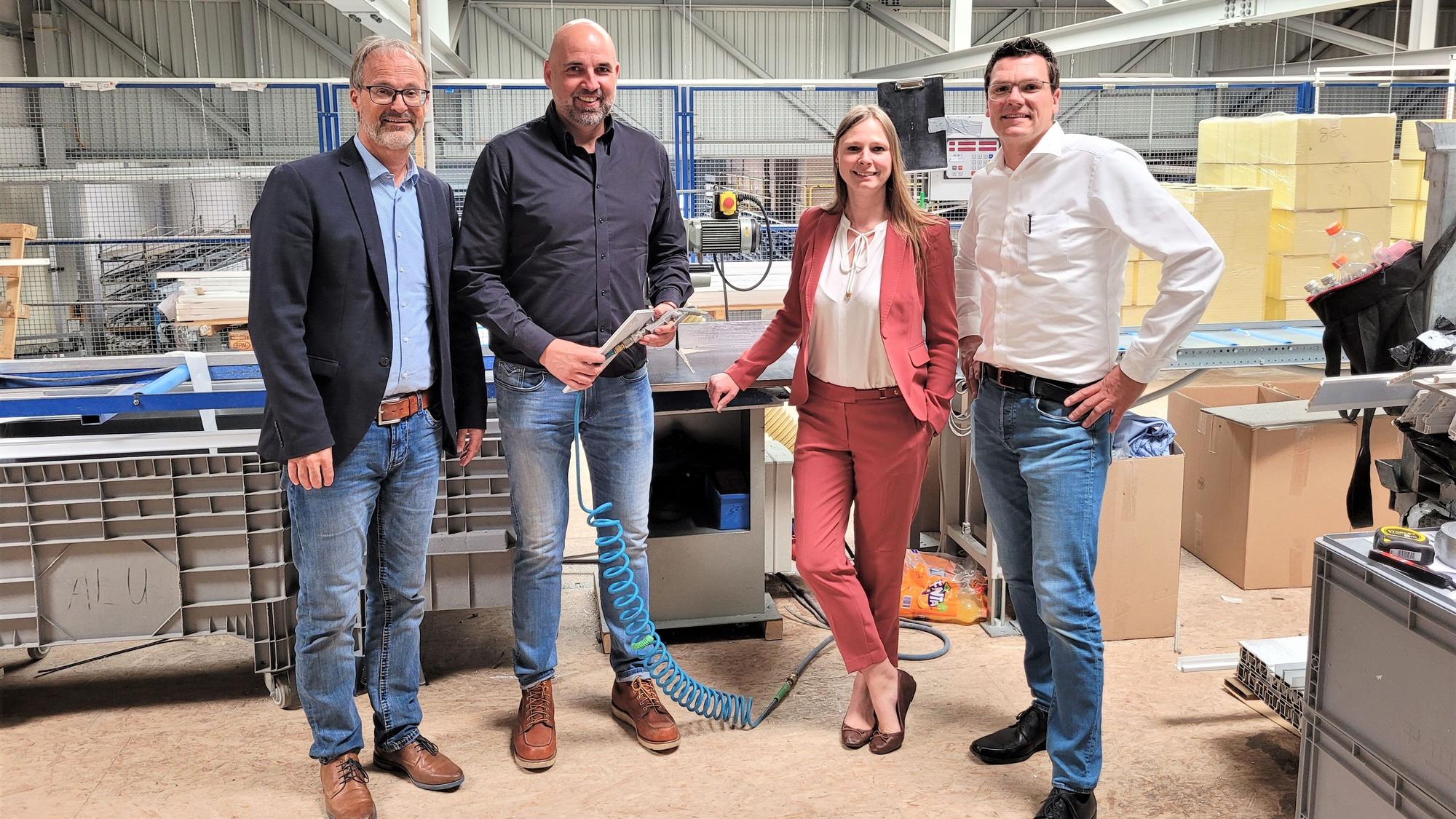 Drei Männer und eine Frau stehen in der Produktionshalle eines Unternehmens in Nettersheim.