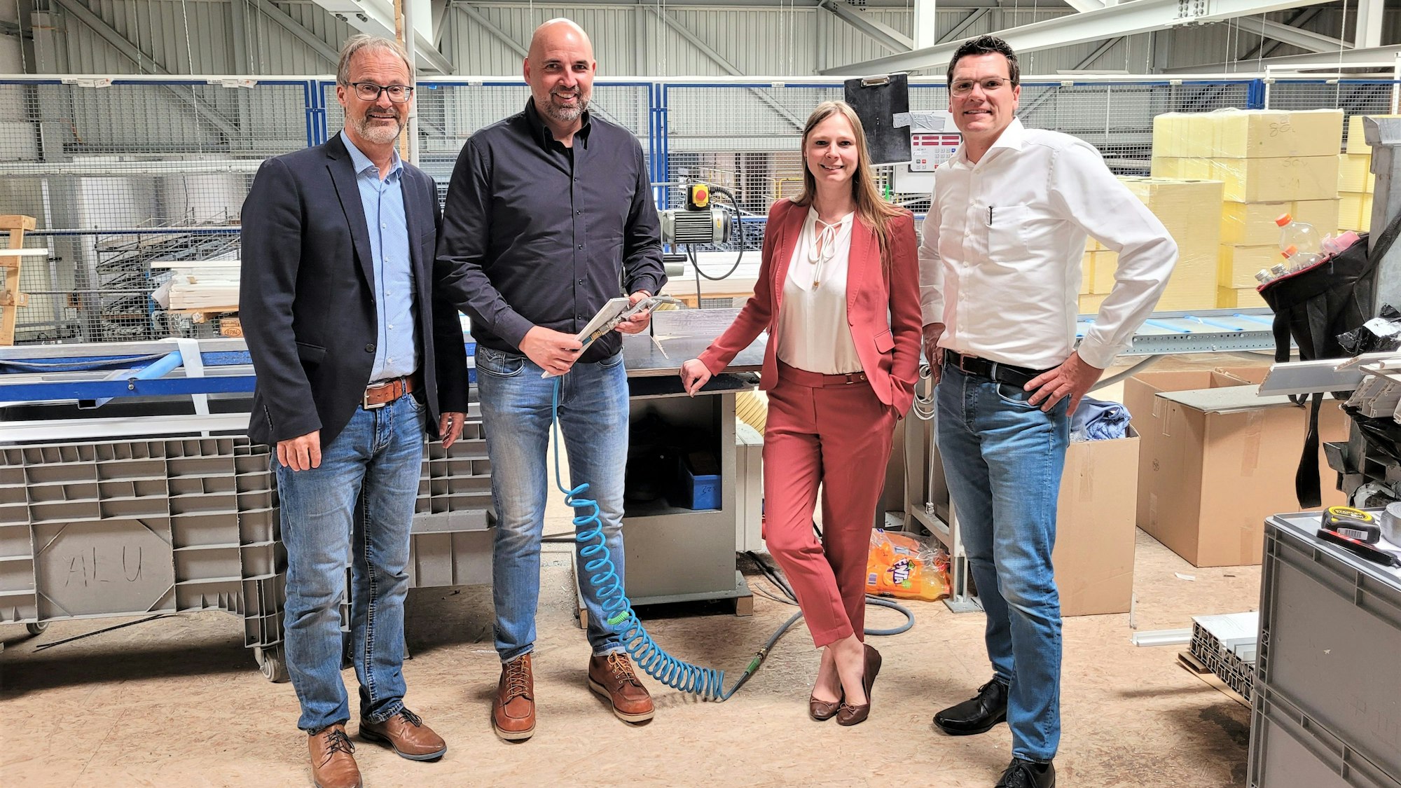Drei Männer und eine Frau stehen in der Produktionshalle eines Unternehmens in Nettersheim.
