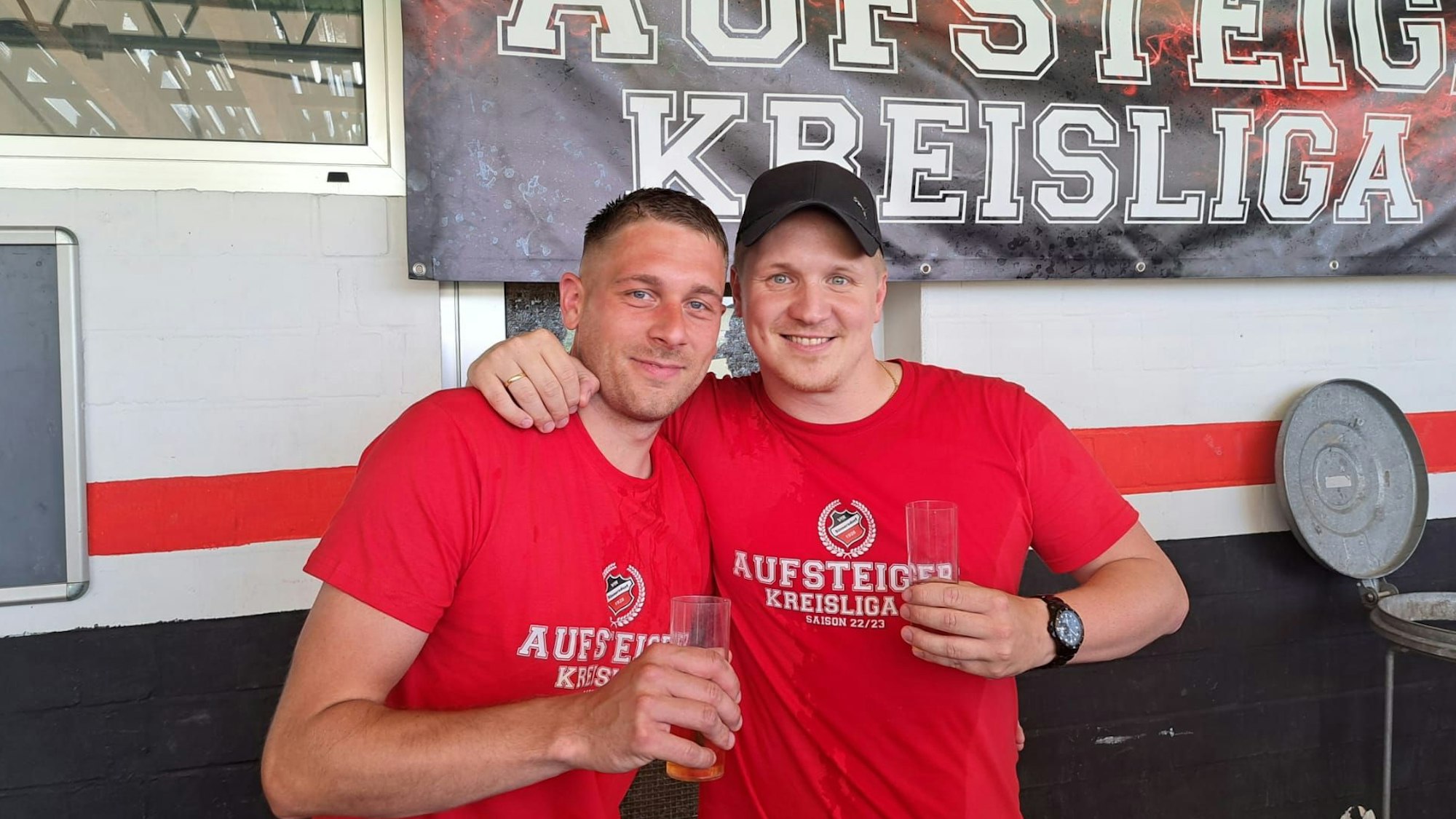 Zwei Fußballer trinken nach dem Aufstieg ein Kölsch.