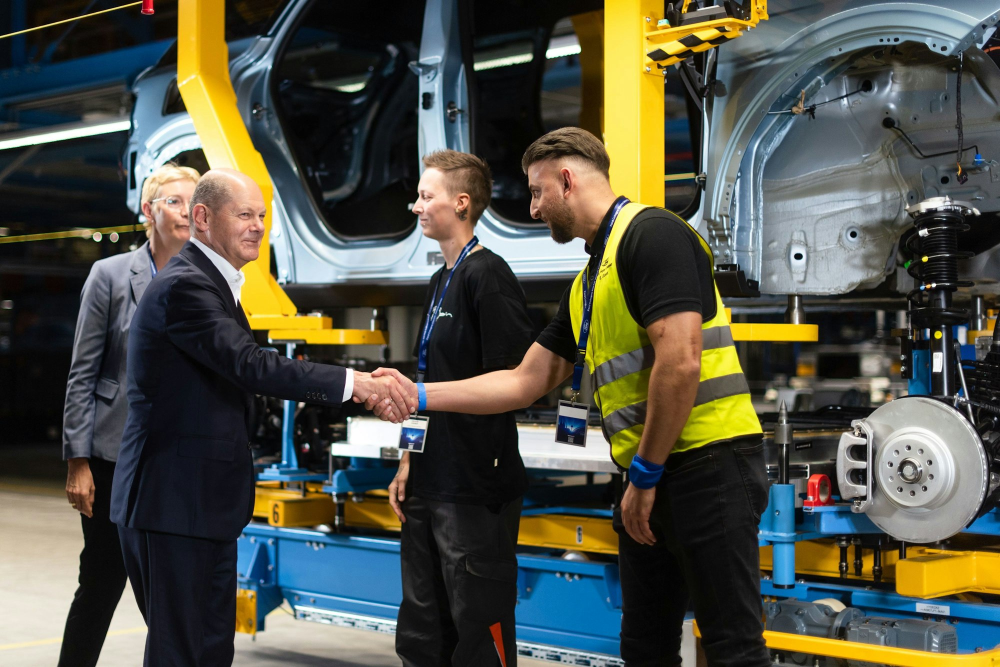 Köln: Bundeskanzler Olaf Scholz (l, SPD) begrüßt bei der Vorab-Eröffnungsfeier des Ford Cologne Electric Vehicle Center Mitarbeiter. Im Hintergrund steht ein Ford Explorer in der Montage.
