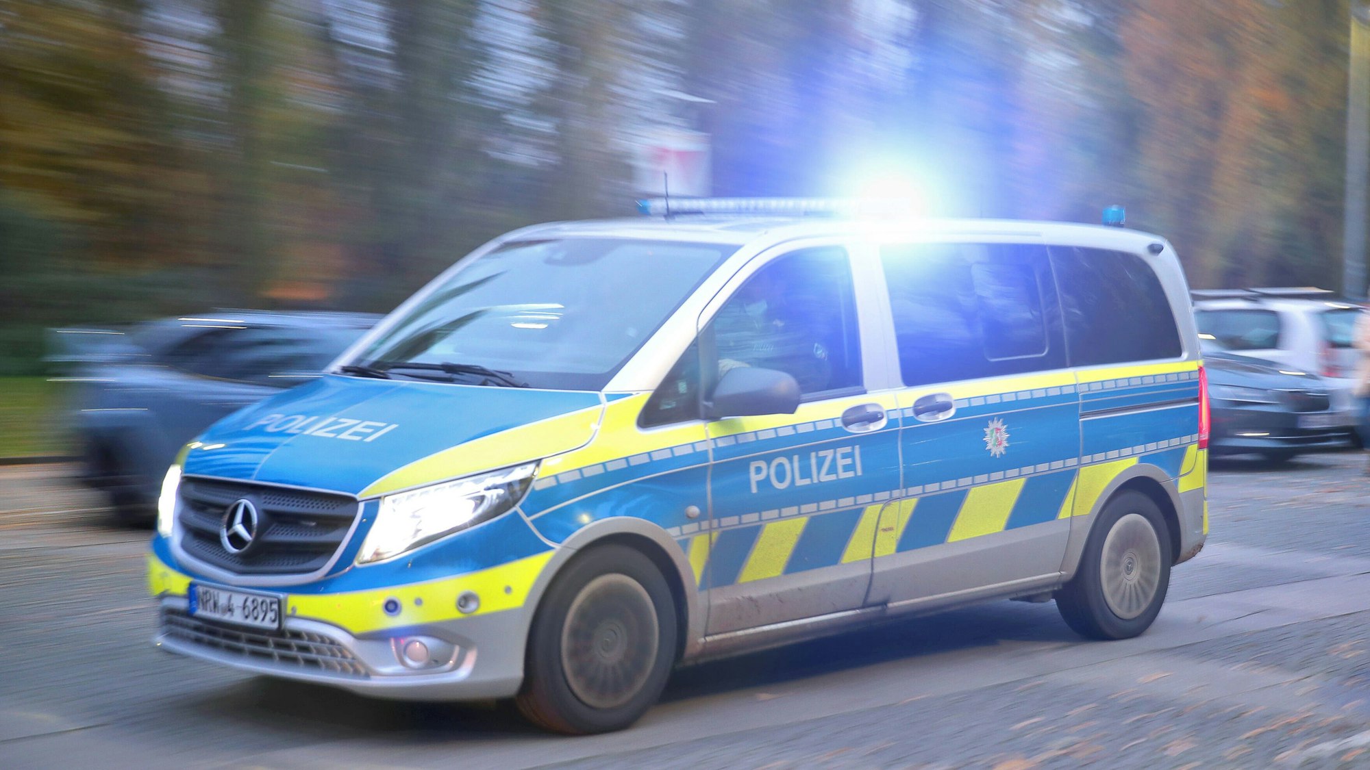 Ein Polizeiauto fährt mit Blaulicht durch eine Straße zum Einsatz.