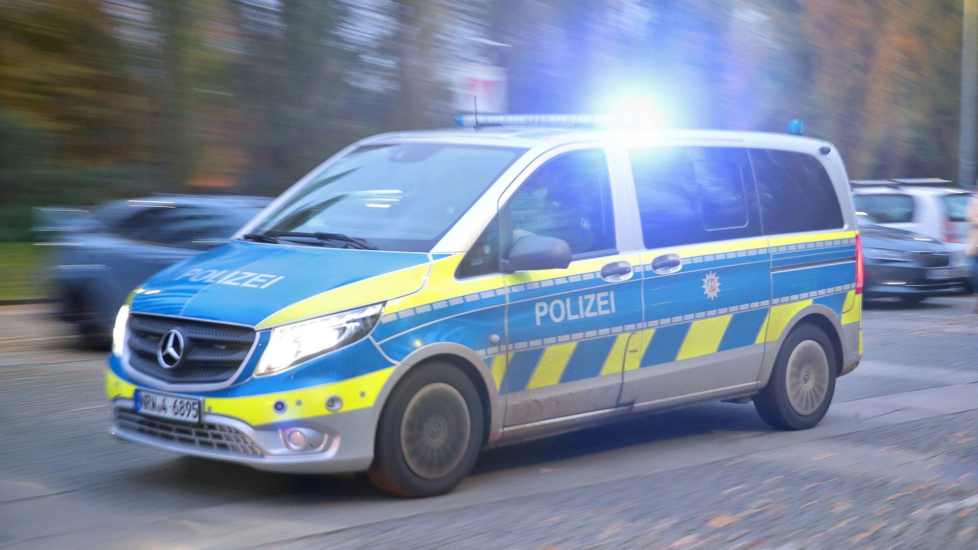 Ein Polizeiauto fährt mit Blaulicht durch eine Straße zum Einsatz.