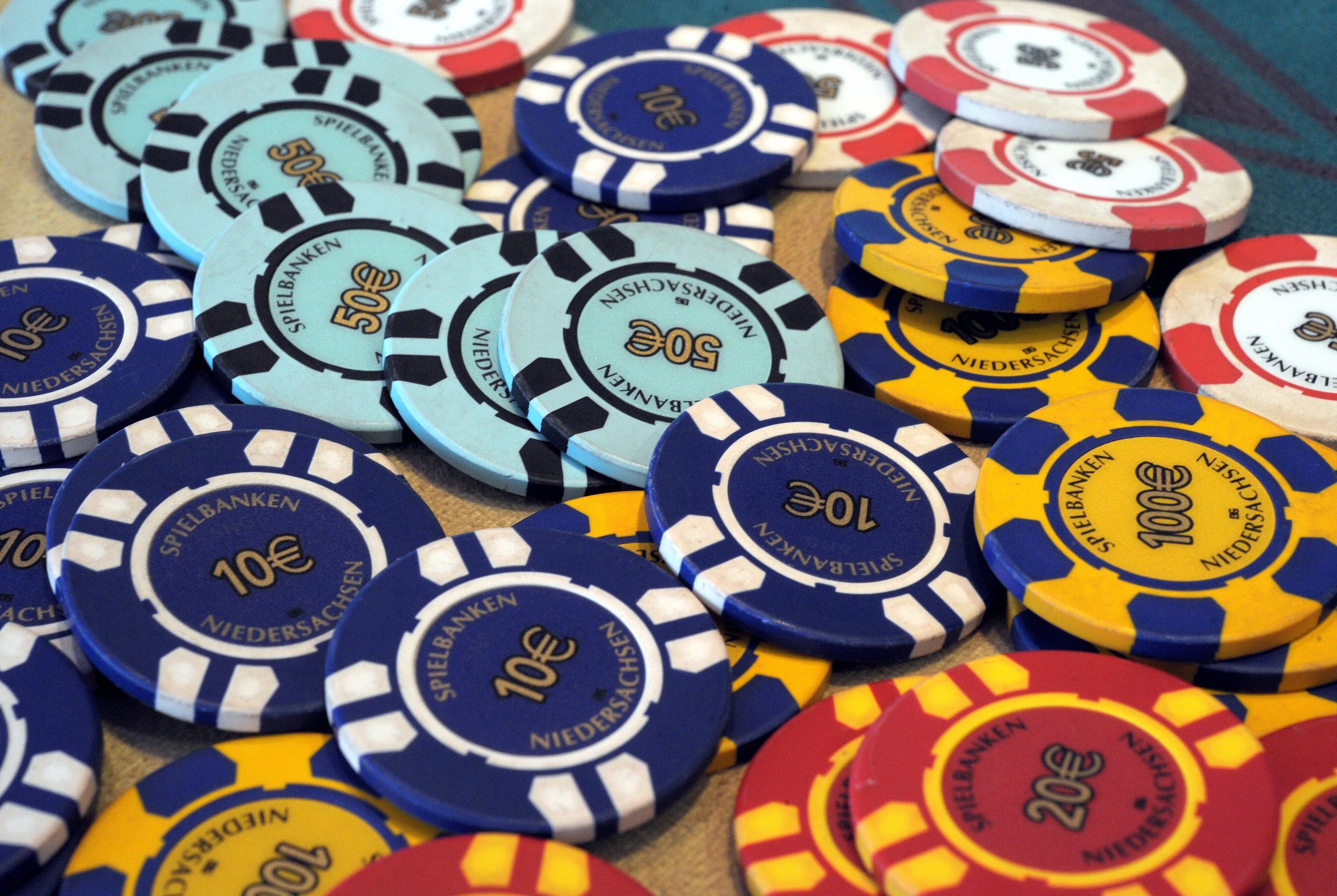 Glücksspielchips liegen auf einem Tisch. Sie haben unteschiedliche Farben.
