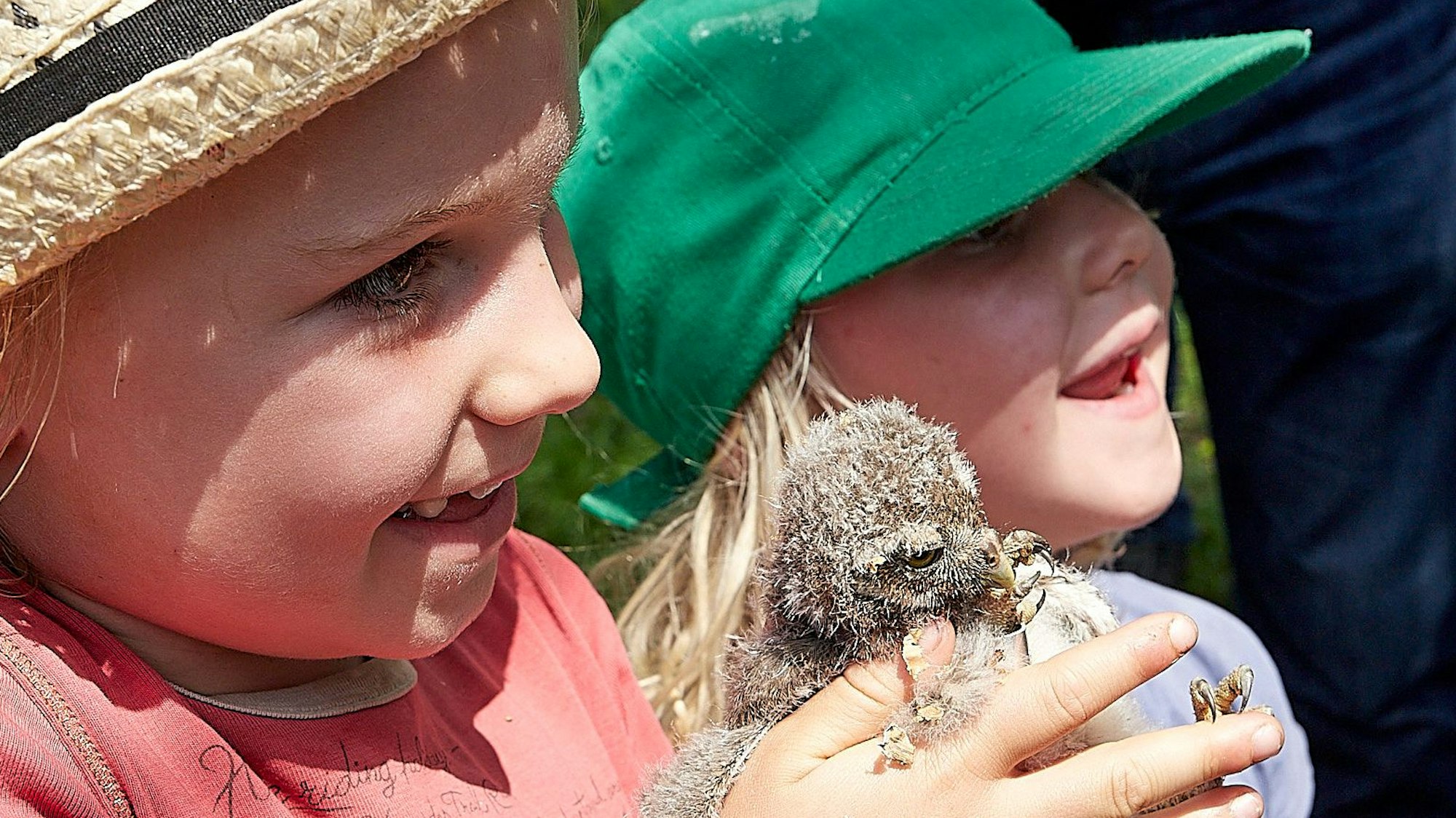 Zwei Kinder halten ein Küken in der Hand.