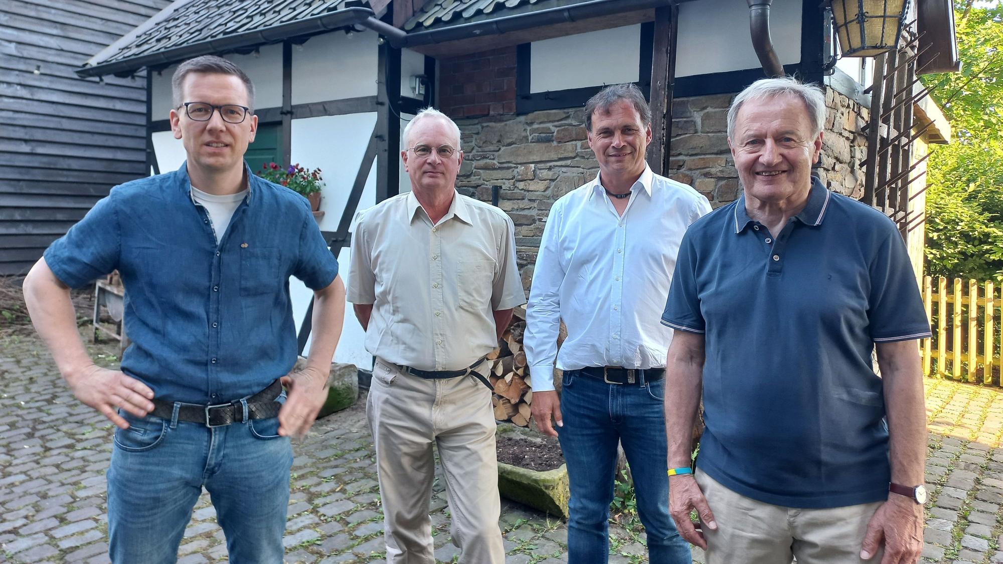 Zu sehen sind vier Männer vor einem historischen Fachwerkhaus.