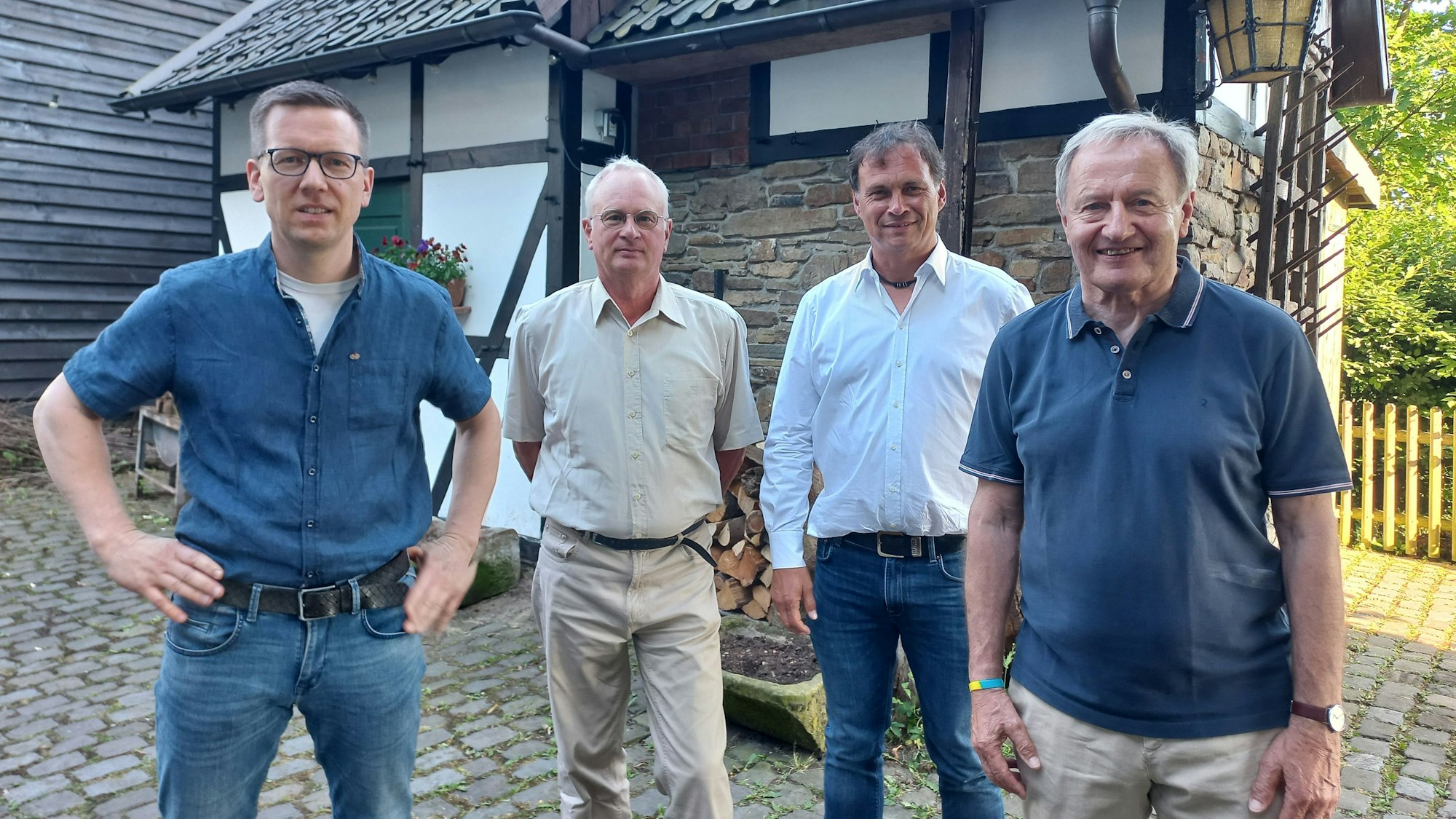 Zu sehen sind vier Männer vor einem historischen Fachwerkhaus.