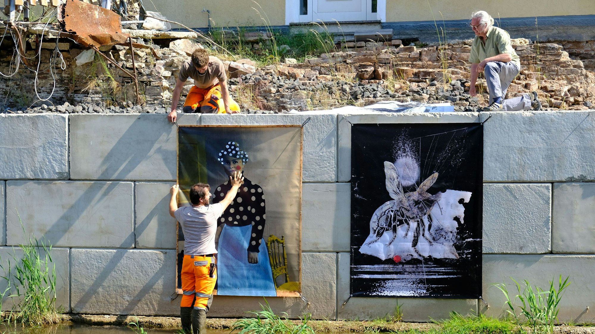 Zwei Bauhofmitarbeiter und der Kurator Jürgen A. Roder installieren die Werke der diesjährigen Ausstellung.