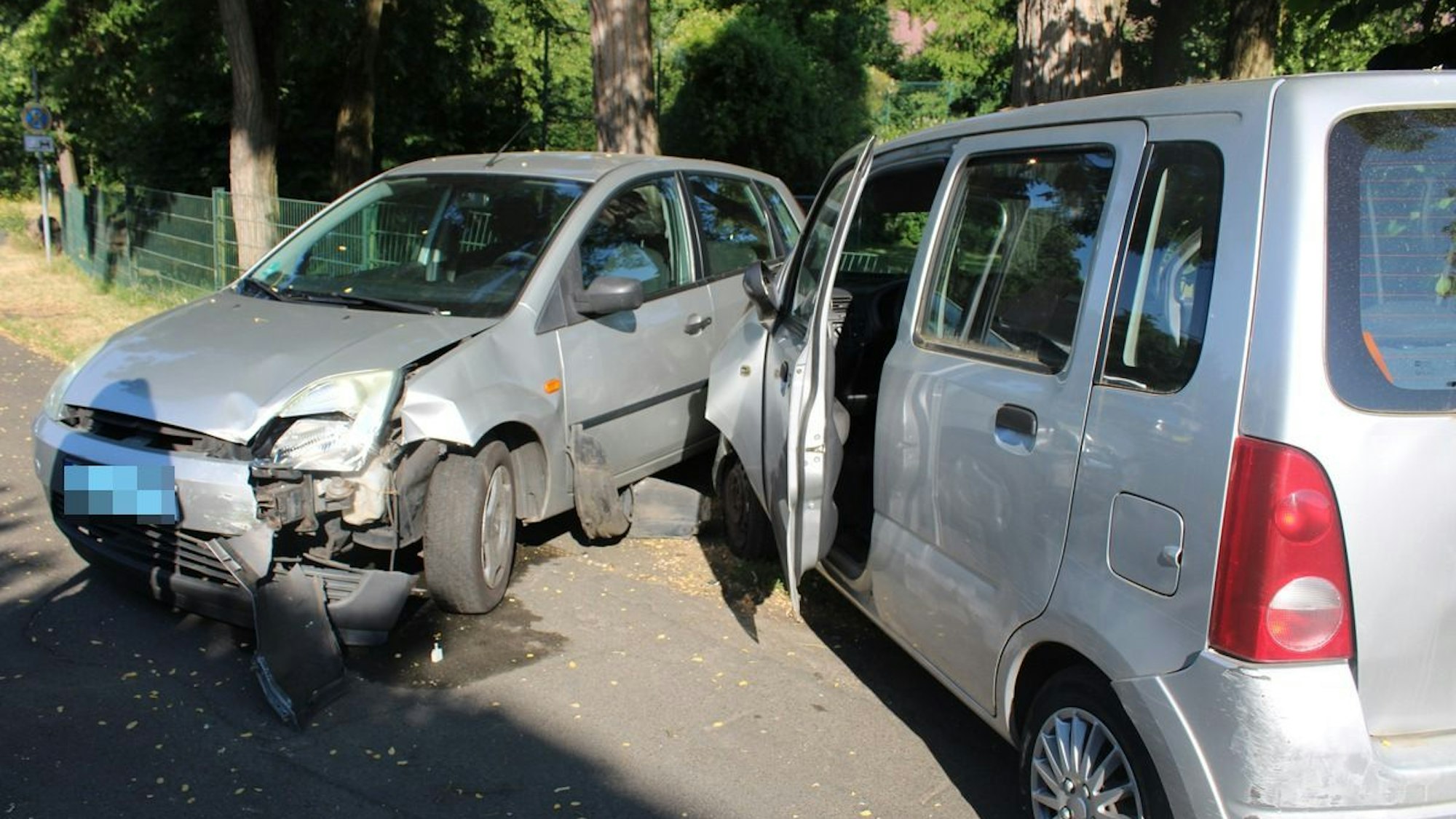 Zwei beschädigte Autos stehen auf einer Straße.