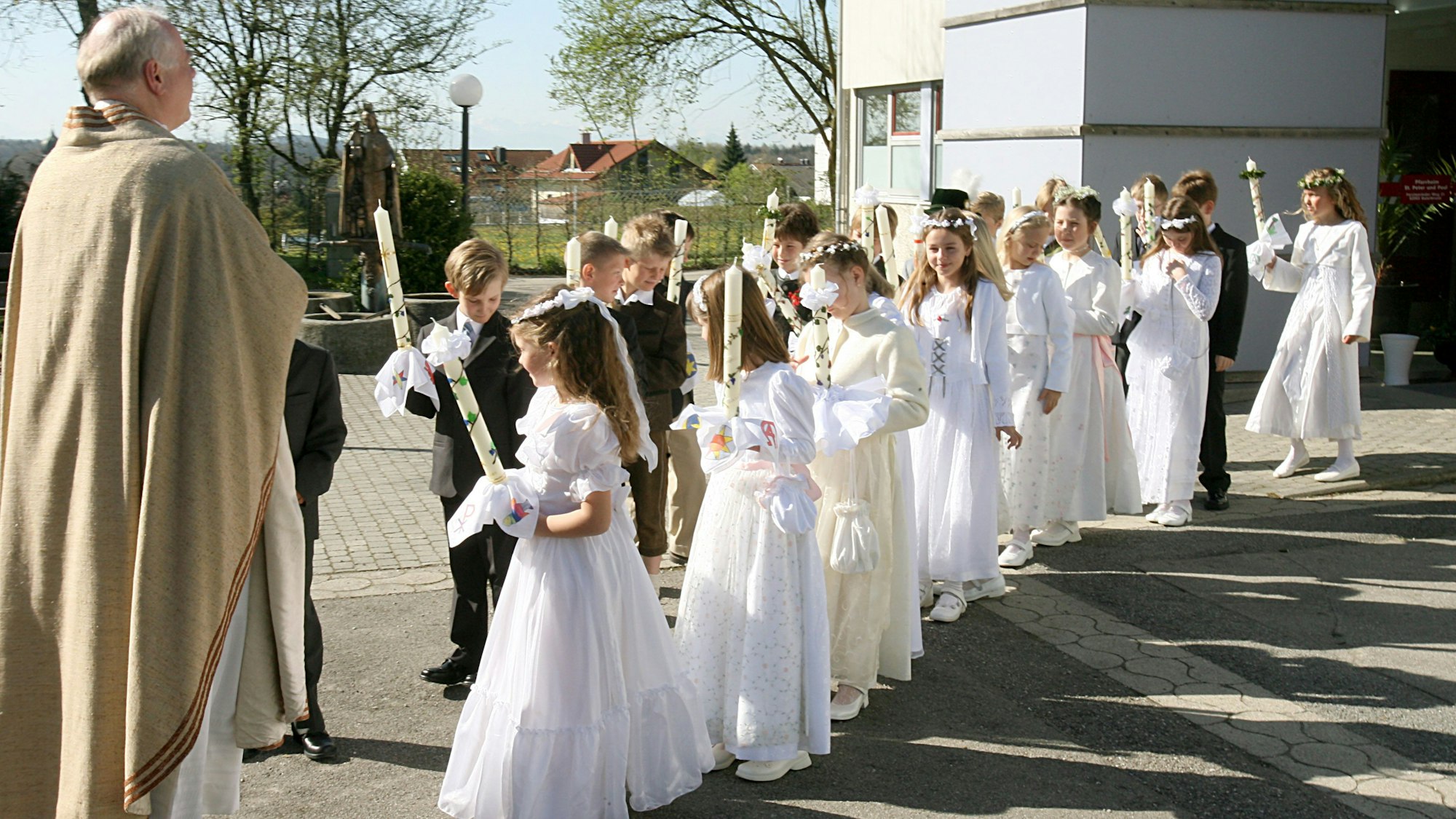 Kinder warten bei der Erstkommunionfeier vor der Kirche.