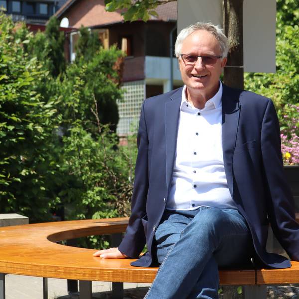 Bernhard Helfer sitzt auf einer der Bänke im neu gestalteten Außenbereich der Schule.